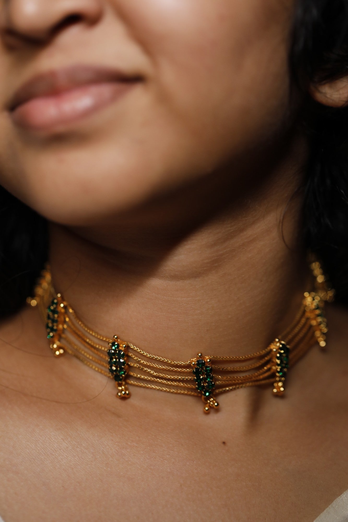 Close-up of a person wearing a gold plated green ad stone choker type necklace