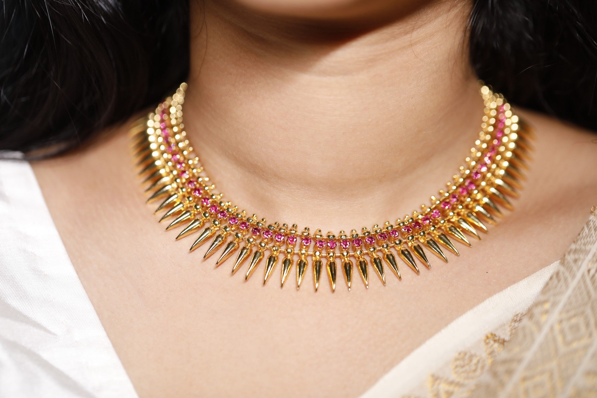 A woman dressed in traditional Kerala attire wearing handcrafted gold-plated Stone Mullamottu jewellery from aambal.store, styled for celebrations.