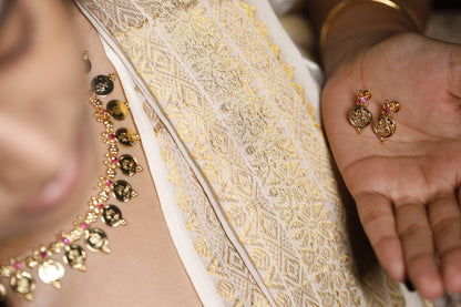 Close-up of a person wearing a gold alike jewellry with traditional lekshmi coin and red AD stone. This can be paired with matching lekshmi studs