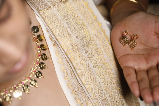 Close-up of a person wearing a gold alike jewellry with traditional lekshmi coin and red AD stone. This can be paired with matching lekshmi studs