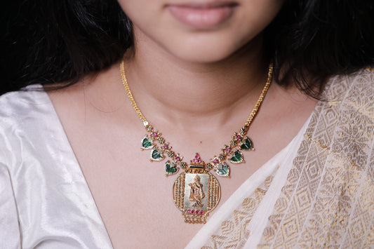 Gold plated short haram type necklace with green palakka stone and red AD stones with palakka motifs worn on a neck. Krishna idol in the pendant design