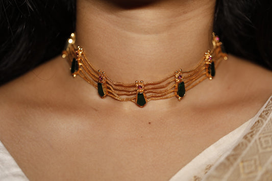Gold plated nagapadam motif green palakka stone choker type necklace on a person's neck