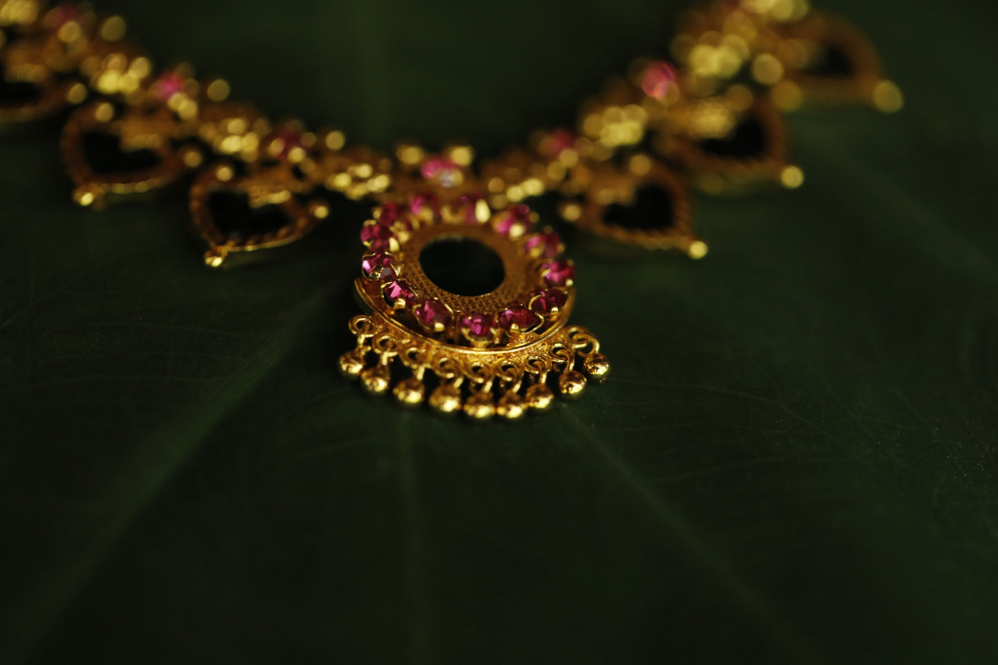 Close-up of a decorative necklace with green palakka stone and red AD stones with kerala traditional Palakka motifs on a green backgrounf